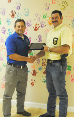 County Attorney Clint Davis presents an iPad to the Henderson County Sheriff's Office Investigator Nick Webb.