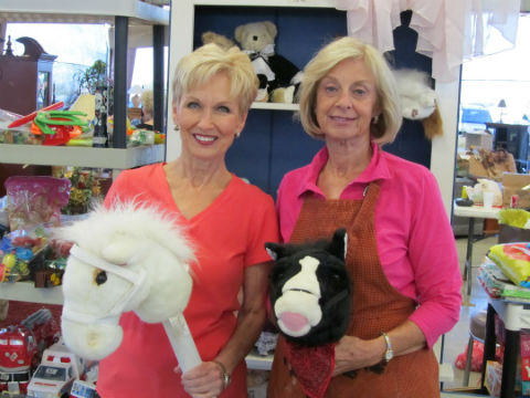 Paula Wideman and Pam Davis, staffers for the Kids’ Room, are admiring the hobby horses donated for the PWC Garage Sale.  The Linens and Kids’ Room were the first sections to sell out this year.