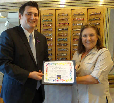 Justin Weiner, Henderson County Assistant District Attorney and the Chairman of the Henderson County Child Welfare Board, (left) presents Athens optometrist Dr. Sherri Robson with a certificate of appreciation for volunteering her services.