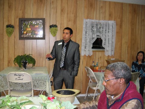 Carlos Padron, Assistant Vice President Branch Manager at Citizens National Bank, speaking to the crowd with Ricky Thomas looking at handouts.